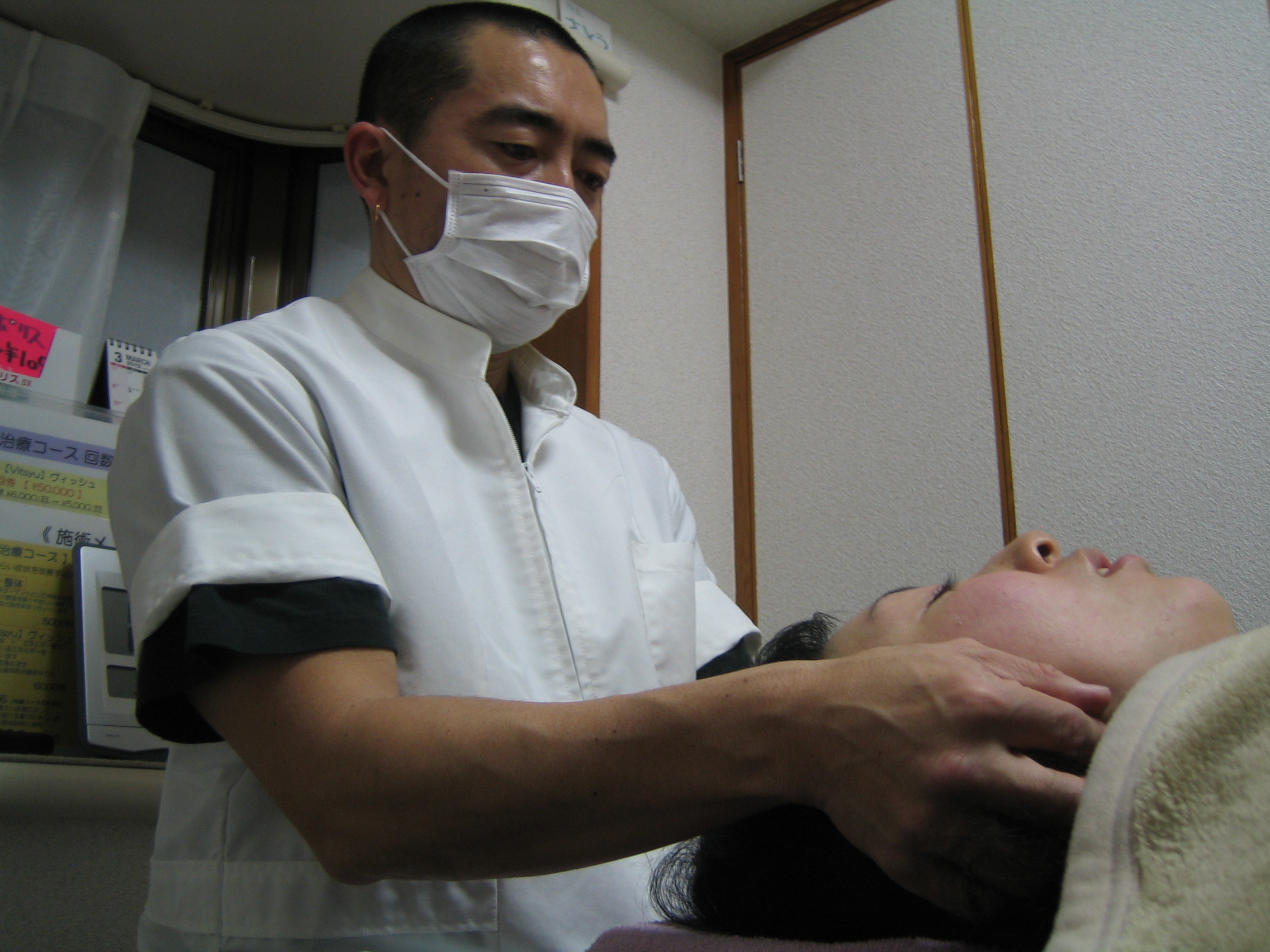 顎まわりを軽いタッチで確認している施術風景